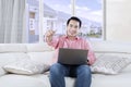 Young Asian person with laptop on couch Royalty Free Stock Photo