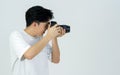 Young asian photographer in white t-shirt looks through the viewfinder while shooting with the camera. Working atmosphere in the