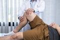 Young asian physiotherapist checking knee joint with injury to giving treatment Royalty Free Stock Photo