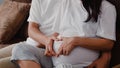 Young Asian Pregnant couple making heart sign holding belly. Mom and Dad feeling happy smiling peaceful while take care baby, Royalty Free Stock Photo