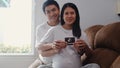 Young Asian Pregnant couple show and looking ultrasound photo baby in belly. Mom and Dad feeling happy smiling peaceful while take
