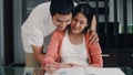 Young Asian Pregnant woman drawing baby in belly and family in notebook. Dad touch his wife belly while happy smiling positive and