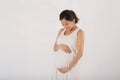 Young Asian pregnant woman expecting new child in white isolated background Royalty Free Stock Photo