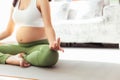 Young asian pregnant woman meditating yoga in lotus position, sitting on yoga mat in living room. Pregnancy mother get peaceful Royalty Free Stock Photo