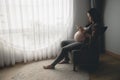 Young asian pregnant woman using mobile phone in living room Royalty Free Stock Photo
