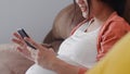 Young Asian Pregnant woman using mobile phone search pregnancy information. Mom feeling happy smiling positive and peaceful while Royalty Free Stock Photo