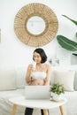 Young Asian pregnant woman working from home using computer and drinking milk for good health of her baby Royalty Free Stock Photo