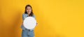 Young asian pretty woman in casual clothing smiling and hold white blank sign board with copy space area for text on yellow panora Royalty Free Stock Photo