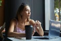 young asian pretty woman sitting at table of cafe with laptop, looking at window Royalty Free Stock Photo