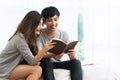 Young asian romantic couple reading book having great time together feeling satisfaction and positive in white bedroom. Close up