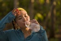 Young Asian runner girl drinking water sweaty and tired. Attractive and exhausted Korean woman thirsty after running workout and Royalty Free Stock Photo