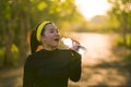 Young Asian runner girl drinking water sweaty and tired. Attractive and happy Korean woman thirsty after running workout and Royalty Free Stock Photo