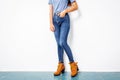 Young girl blue jeans brown shoes wall white. Royalty Free Stock Photo