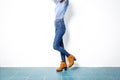 Young girl blue jeans brown shoes wall white. Royalty Free Stock Photo