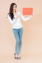 Young asian smiling woman holding red advertising sign board. Isolated portrait on orange background with copy space Royalty Free Stock Photo