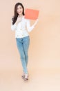 Young asian smiling woman holding red advertising sign board. Isolated portrait on orange background with copy space Royalty Free Stock Photo