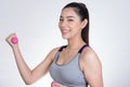 Young asian sporting woman training with dumbbell. Pretty athletic girl making physical exercise against white background. Health