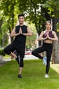 young asian sportsman and sportswoman standing in vrksasana Royalty Free Stock Photo