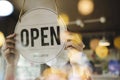 Young asian staff woman wearing protection face mask turning open sign board on glass door Royalty Free Stock Photo