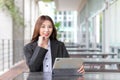 Young Asian student in a navy blue uniform sits happily confidently working and looking at the camera as she works using her Royalty Free Stock Photo