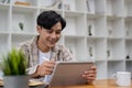 Young asian student using digital tablet remote studying, watching online webinar, zoom virtual training on video call Royalty Free Stock Photo