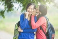 Young Asian student wishpering something to her friend, smiling Royalty Free Stock Photo