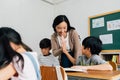 Young Asian teacher giving boy high five in school, success, achievement, happiness. Asia school boy with young woman in