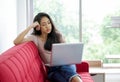 Young asian teen use laptop computer on the red sofa to prepare for exams in the living room Royalty Free Stock Photo