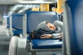 Young Asian teenage boy, solo traveller sleep on seat in modern airport terminal, listen to music