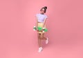 Young asian teenage girl holding skateboard with wearing wireless headphones listening to music on pink background Royalty Free Stock Photo