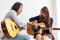 Young Asian teenager is learning to play guitar by professional teacher who showing simple chords for music class school Royalty Free Stock Photo