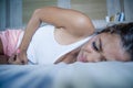 Young Asian Thai or Malay woman lying in bed holding stomach belly suffering month menstruation period pain and tummy cramps feeli Royalty Free Stock Photo