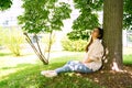 Young Chinese woman sitting dreaming in shadow under green tree on sunny day Royalty Free Stock Photo