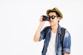 Young Asian tourist with hat and sunglasses smiling and holding camera isolated over white background. Royalty Free Stock Photo