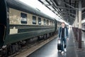 Young Asian tourist with luggage waiting train in station.