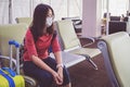 Young Asian tourist woman with mask sitting with distance at the airport