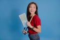 Young Asian tourists smiling. She was holding a map and a camera and looked at the empty space of the blue background Royalty Free Stock Photo