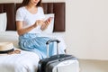 Young Asian traveler in white T- shirt relaxing and using smartphone in hotel room after check in. Travel concept