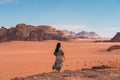 Young Asian traveller with local Arab dress standing on top of mountain and enjoying landscape of Wadi Rum desert, Jordan, Arab