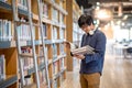 Young Asian university student reading book in library Royalty Free Stock Photo