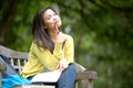 Young asian university student sitting on wooden bench in park Royalty Free Stock Photo