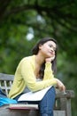 Young asian university student sitting on wooden bench in park Royalty Free Stock Photo