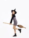 Young asian witch girl in black halloween costume wearing witch hat and holding broom smiling and posing on white background Royalty Free Stock Photo