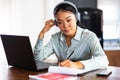 Young Asian woman attending online foreign language classes. Sitting in front of laptop computer with headphones listening course Royalty Free Stock Photo