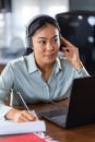 Young Asian woman attending online foreign language classes. Sitting in front of laptop computer with headphones listening course Royalty Free Stock Photo