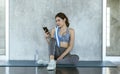 Young asian woman attractive smiling active fitness sitting on the floor of the gym and using smartphone Royalty Free Stock Photo