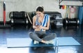 Young asian woman attractive smiling active fitness sitting on the floor of the gym and using smartphone