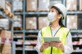 Young asian woman auditor or trainee staff wears mask working during the COVID pandemic in store warehouse shipping industrial.