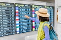 asian woman with backpack in international airport looking at the flight information timetables board Royalty Free Stock Photo