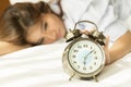 Young Asian woman in bed trying to wake up with alarm clock Royalty Free Stock Photo